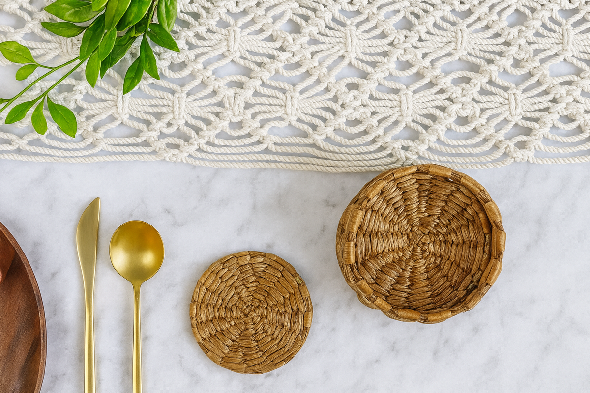 Water hyacinth wicker coasters on a marble surface with gold cutlery and a macrame wall hanging Boho dining and decor